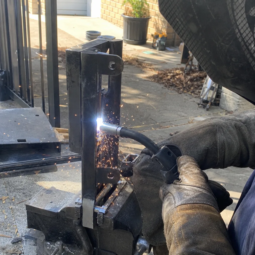 Metalworker performing MIG welding on custom steel gate hardware nationwide